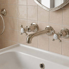 Brushed nickel wall-mounted bathroom tap set with two cross handles and a curved spout