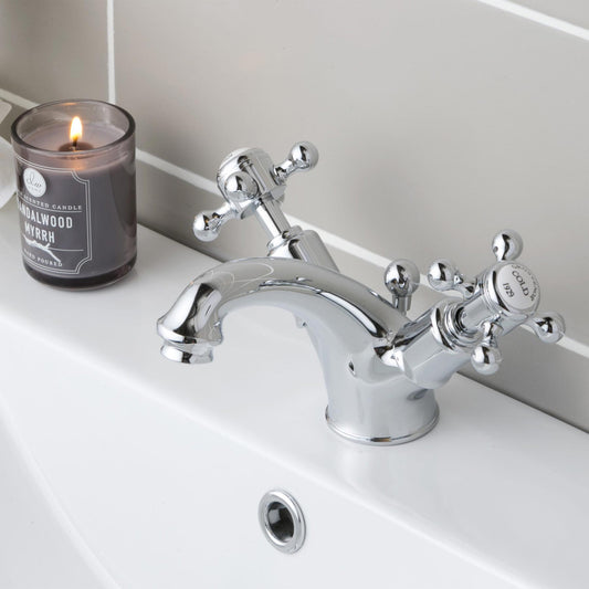 Two handles crosshead  basin mixer tap installed on a basin with a burning candle next to it 1800